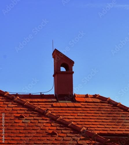 schornstein auf braunem ziegeldach, heizperiode, blauer himmel, teuerung, strenger winter photo