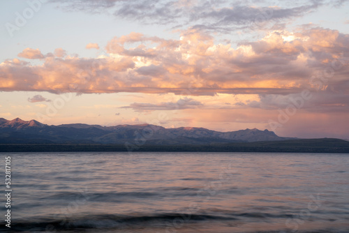 Long exposure shot of Nahuel Huapi lake at sunset. Beautiful blurred water effect and mountains in the horizon with dusk colors.