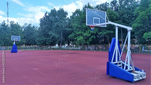 The basketball court is arranged on the rubberized surface of the stadium. Basketball shields with rings and baskets are fixed on metal structures with soft fences. The stadium is fenced