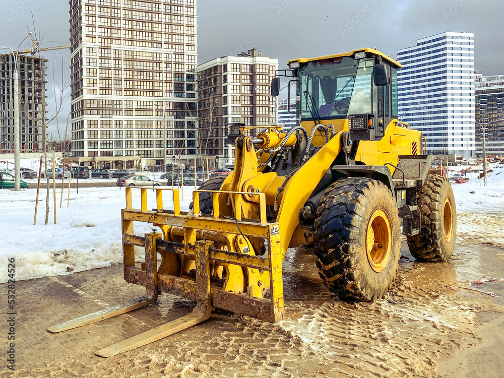 construction equipment on site. construction of houses. bright, yellow forklift transports heavy loads with a metal attachment. lifting, large, construction machinery