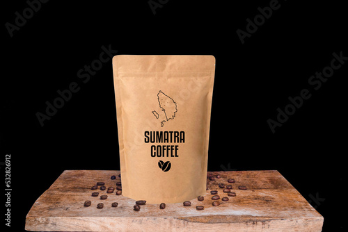 Sumatra coffee beans and eco friendly kraft paper package on wooden board with black isolated background