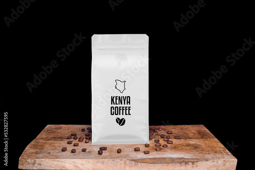 Kenya coffee beans and white package on wooden board with black isolated background