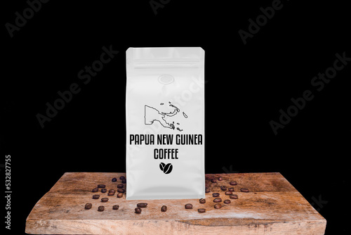 Papua New Guinea coffee beans and white package on wooden board with black isolated background