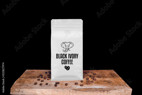 Black Ivory coffee beans and white package on wooden board with black isolated background