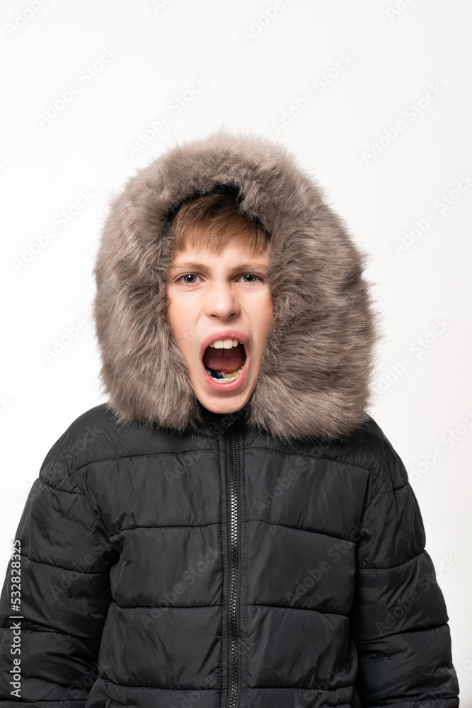 A boy in a winter jacket with a hood on a white background. A boy in a winter jacket with a hood on a white background.