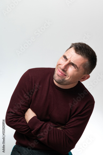 A man touches his stomach with two hands, on a white background with copy space, Stomach pain in a man.