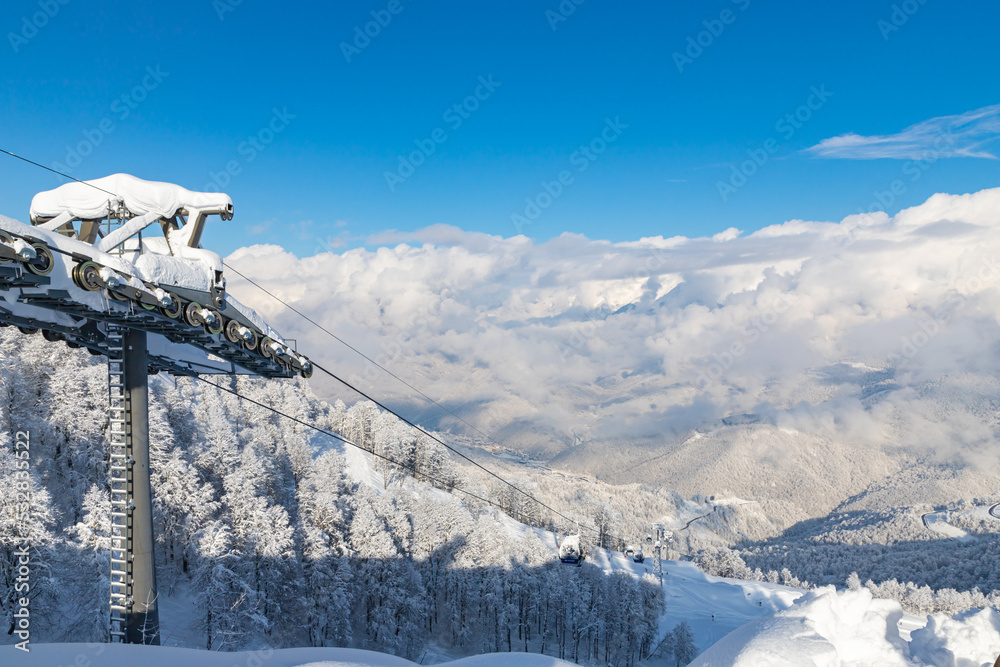 Panoramic view of ski lift with ski slopes and mountain background in Rosa Khutor ski resort. Cloudy weather. Sochi, Russia