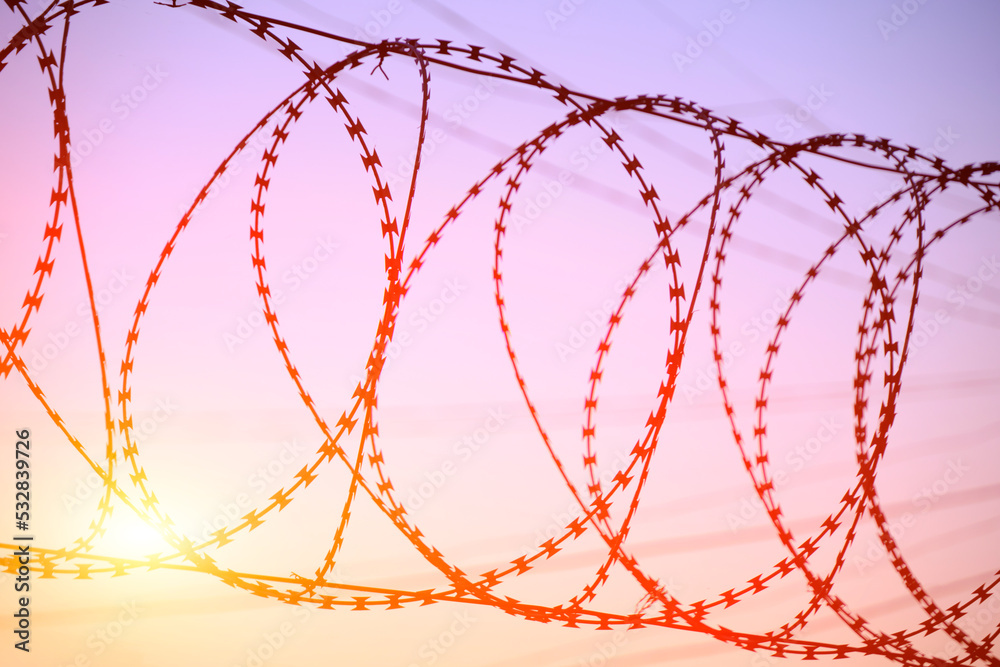 Fence with barbed wire background bright red setting sun. Fence with barbed wire background bright red setting sun.