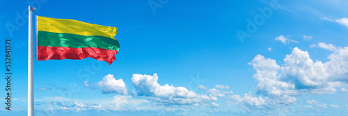 Lithuania flag waving on a blue sky in beautiful clouds - Horizontal banner