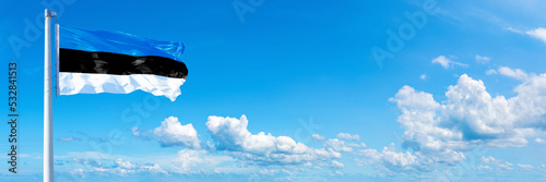 Estonia flag waving on a blue sky in beautiful clouds - Horizontal banner