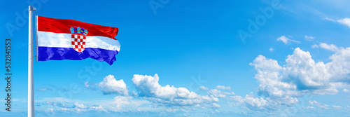 Croatia flag waving on a blue sky in beautiful clouds - Horizontal banner
