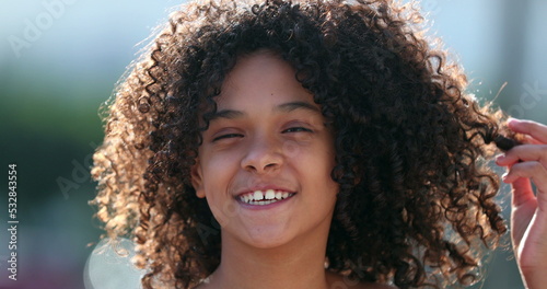 African preteen girl smiling at camera. Black child standing outside with curly hair.mov