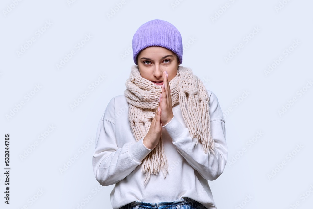 Winter portrait of young female in sweater hat scarf, on light studio background Winter portrait of young female in sweater hat scarf, on light studio background