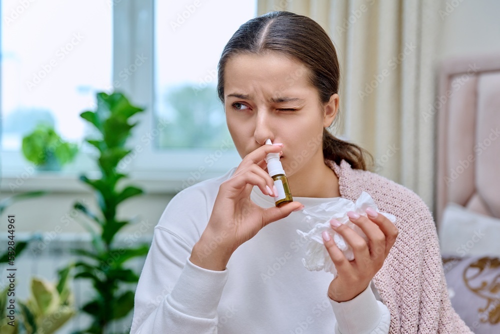 Teenage girl with runny nose treating rhinitis using nose drops spray Teenage girl with runny nose treating rhinitis using nose drops spray