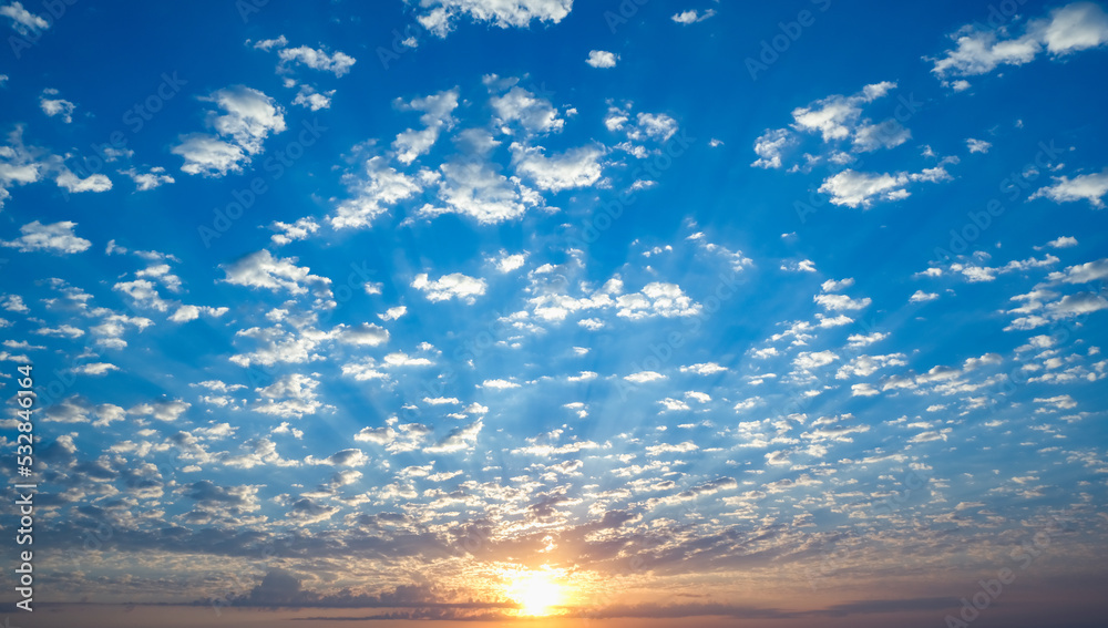 Obraz premium Blue sky with twilight clouds. The sun is setting over the horizon. Yellow dawn. Red sunset. Pink clouds.