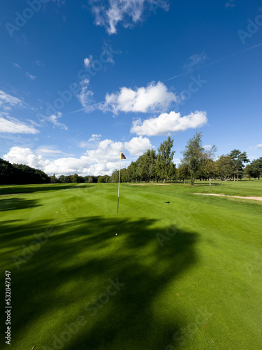 Flag and the hole at golf club blue sky summers day with some clouds