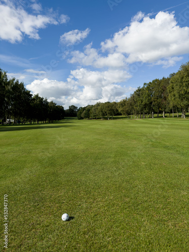 Flag and the hole at golf club blue sky summers day with some clouds