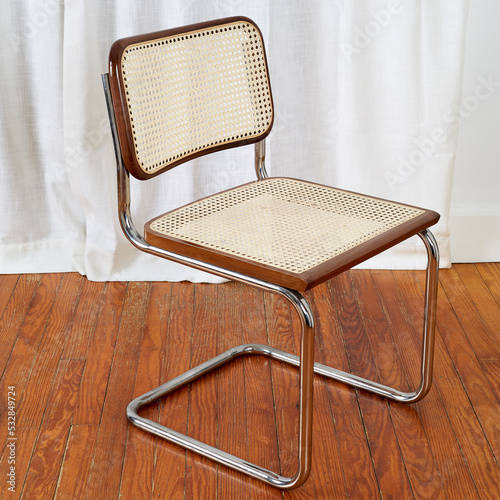 фотографія Angle view Cane and chrome Cesca style cantilever chair on wood floor before lux