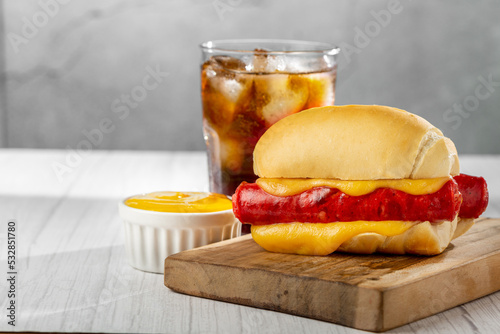 Cheese and sausage sandwich with soda glass.