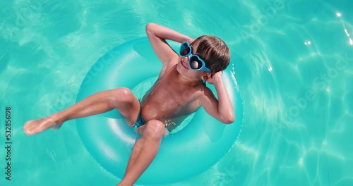 Happy child having fun on summer vacation. Kid playing in swimming pool. Top view portrait of funny boy. Active healthy lifestyle concept. Slow motion