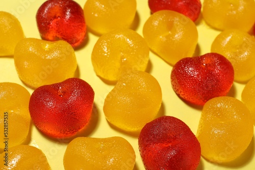 Delicious gummy cherry candies on yellow background, closeup
