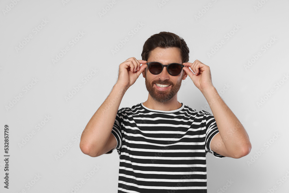 Portrait of smiling bearded man with stylish sunglasses on grey background Portrait of smiling bearded man with stylish sunglasses on grey background