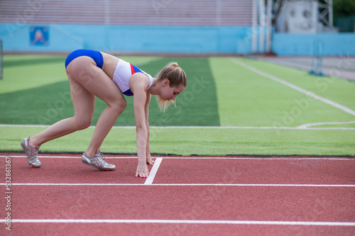 Female runner in the stadium is ready to race.