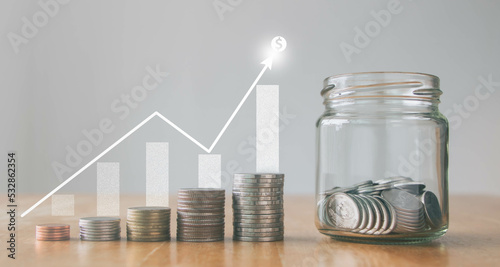 Concept of saving money for the future. Coins in a jar with money stack step growing growth saving money and graph US dollar sign, finance business investment. Savings deposit coins in a glass bottle.