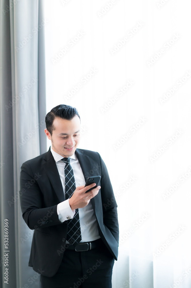 Happy young Asian man looking at his smartphone and celebrating victory isolated on white background. Happy young Asian man looking at his smartphone and celebrating victory isolated on white background.