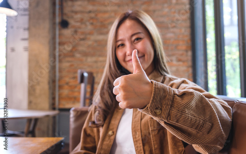A young woman making and showing thumbs up hand sign