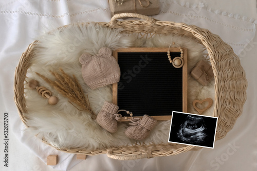 Letter board Baby Announcement with basket. Baby Clothing Mock Up . Space for design . Pregnancy announcement background with blurred . Selective focus photo