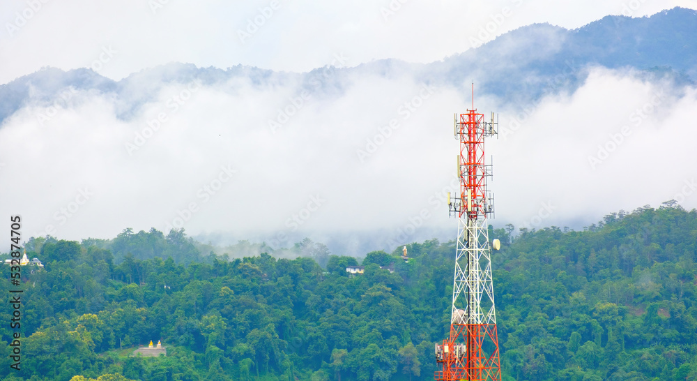 Mobile phone tower against the mystery background of evening fog or rain clouds at the mountains. 