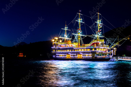 Silhouette of Mount Fuji with torii gate and lit up sail boat on Lake Ashi Hakone Japan