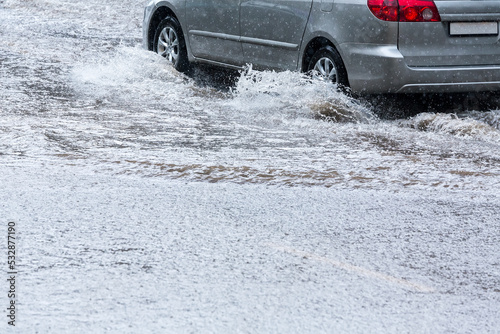Картината върху платно car driving through rain puddles with splashing water on flooded street