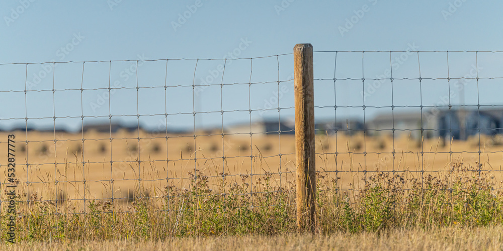 Fototapeta premium wire fence with farm fields behind it