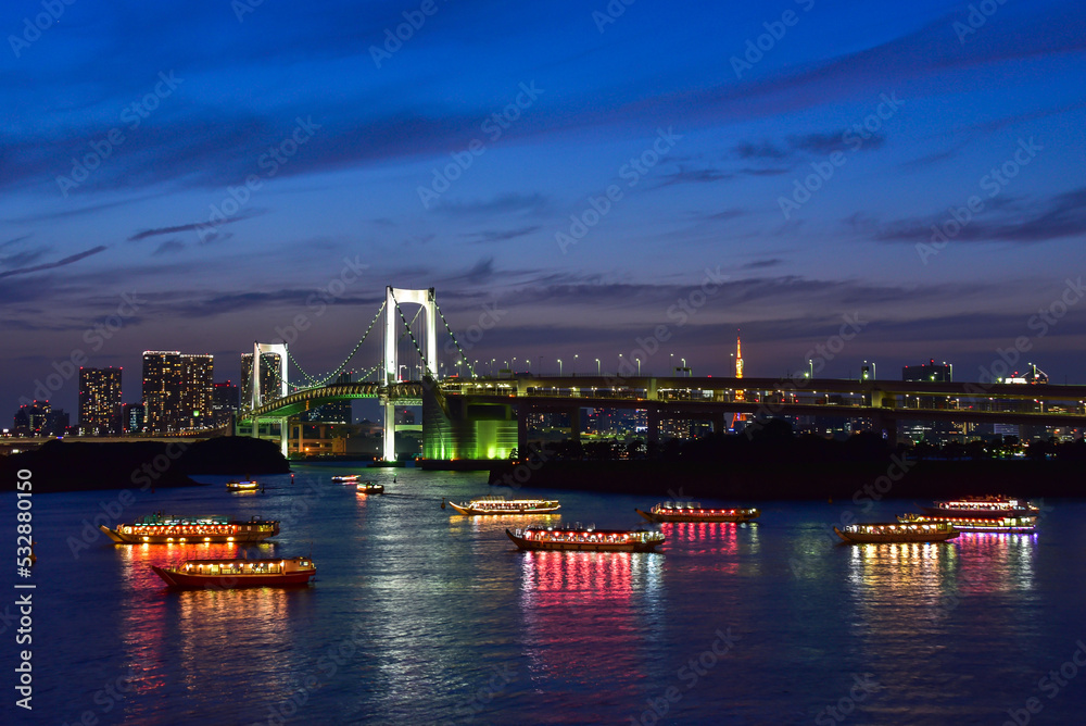 Rainbow bridge at night with yakatabune japanese party boats in tokyo
