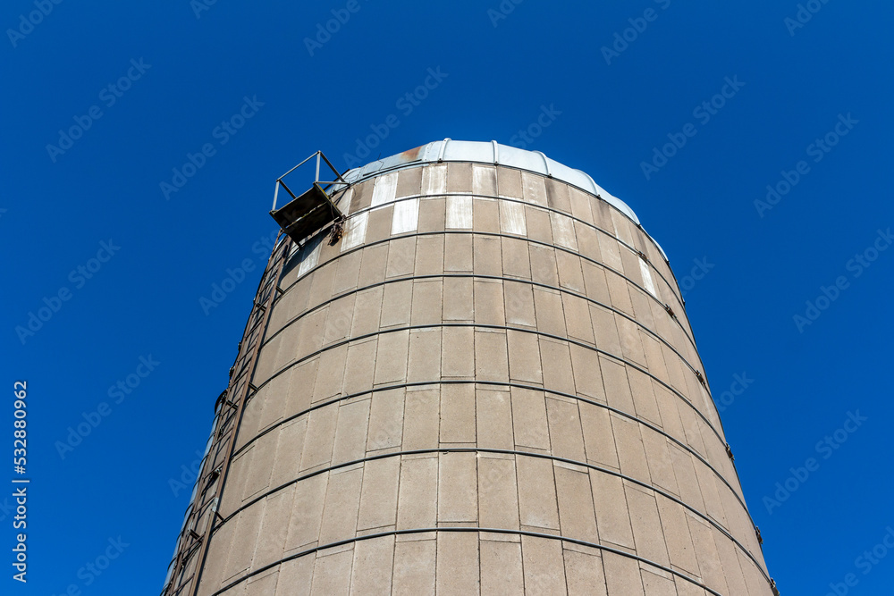 Low angle abstract texture view of a rustic old concrete silo wall with blue sky background, showing natural weathering from age Low angle abstract texture view of a rustic old concrete silo wall with blue sky background, showing natural weathering from age