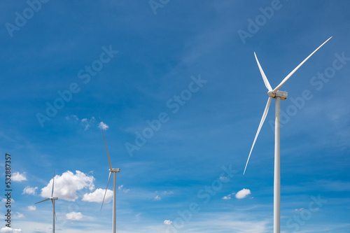 Electricity generating white large wind turbine standing against blue sky background in a windy zone area in southeast Asia.