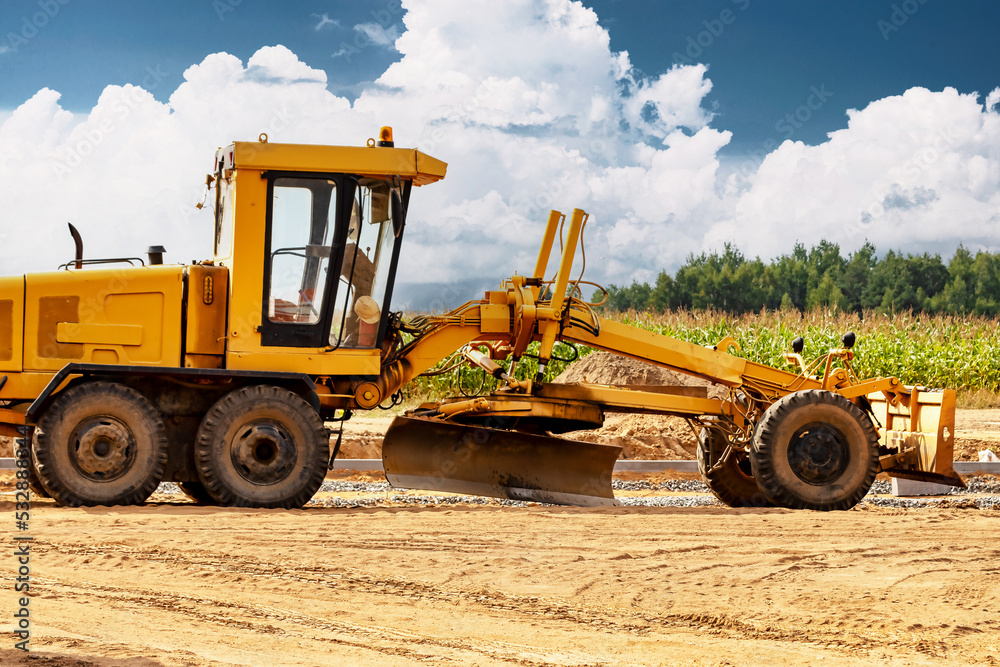 Road grader at the construction site. Powerful construction machine for ground leveling and excavation. Close-up. Professional construction equipment. Road grader at the construction site. Powerful construction machine for ground leveling and excavation. Close-up. Professional construction equipment.