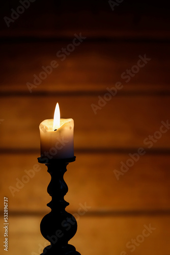 Candle and dramatic lighting on brown wooden background.