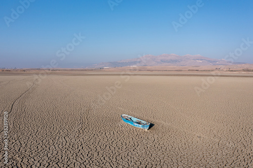 Extreme drought condition on a lake. Abandoned boat is seen at the bottom of a river. Climate change, global warming concept