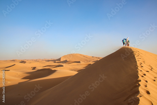 Group huddled on top of a sand dune in the Sahara, Morocco