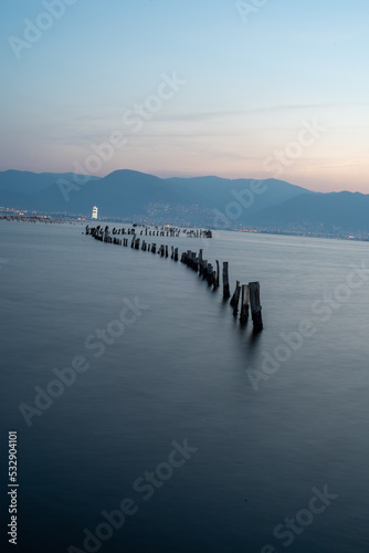 City view with ruins of pier on the sea  after sunset the city lights are on and sky is getting dark