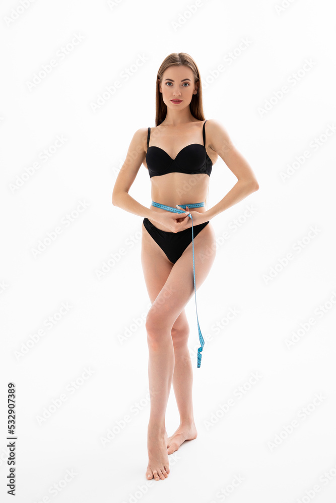 Young woman measures her waistline with measuring tape Young woman measures her waistline with measuring tape
