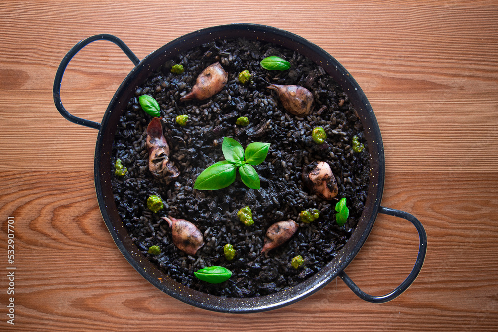 Black paella with squid and pistachio pesto. Tapa paella typical recipe