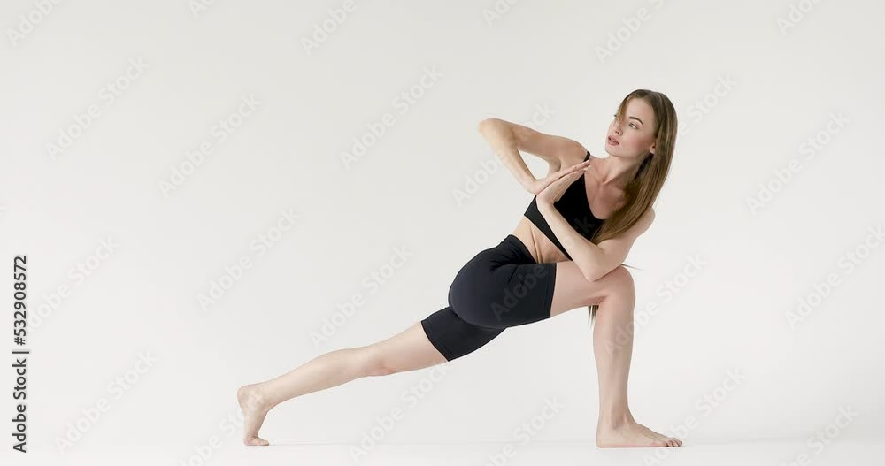 Beautiful brunette fitness woman in black sportswear doing yoga on a white background Beautiful brunette fitness woman in black sportswear doing yoga on a white background