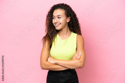 Young hispanic woman isolated on pink background looking to the side and smiling