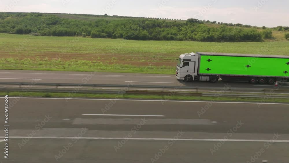 Aerial view of a driving truck with chroma key greenscreen place on the side of its body