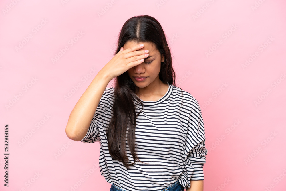Young Colombian woman isolated on pink background with headache