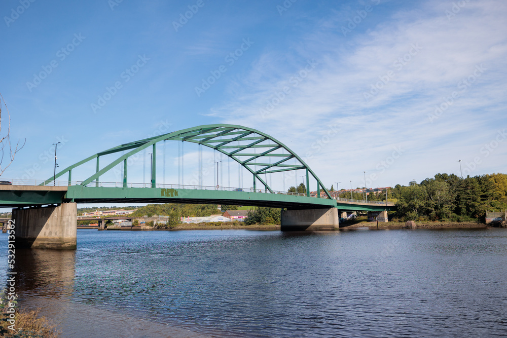 Naklejka premium Blaydon England: 17th Sept 2022: View of Newcastle upon Tyne's Scotswood Bridge from the Tyne River in Blaydon. Sunny day with blue sky and light clouds